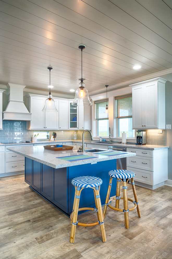 Beach style l-shaped kitchen in Houston with an undermount sink, shaker cabinets, white cabinets, blue splashback, subway tile splashback, light hardwood floors, with island and beige floor.