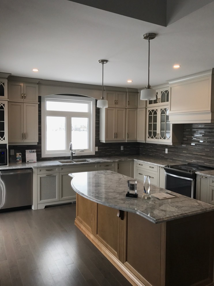 Inspiration for a mid-sized transitional l-shaped medium tone wood floor and brown floor kitchen remodel in Ottawa with an undermount sink, shaker cabinets, white cabinets, quartz countertops, gray backsplash, matchstick tile backsplash, stainless steel appliances and an island