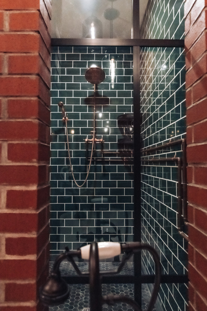 Inredning av ett industriellt badrum, med klinkergolv i keramik, grått golv, dusch med gångjärnsdörr, grön kakel och tunnelbanekakel