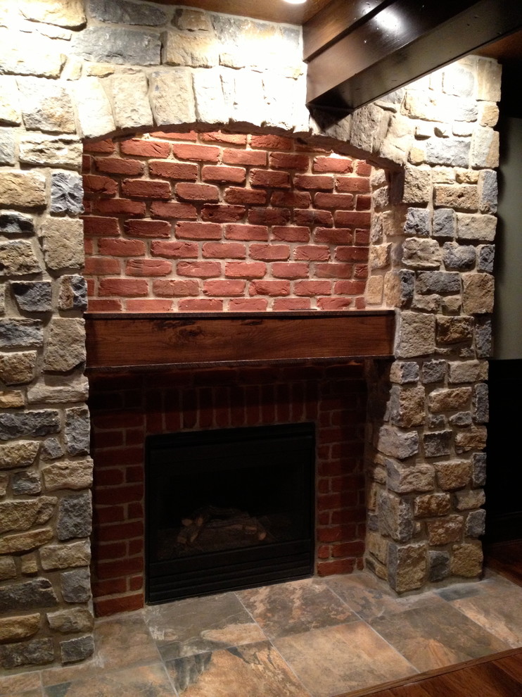 Basement - small rustic walk-out basement idea in Cincinnati with gray walls, a standard fireplace and a stone fireplace