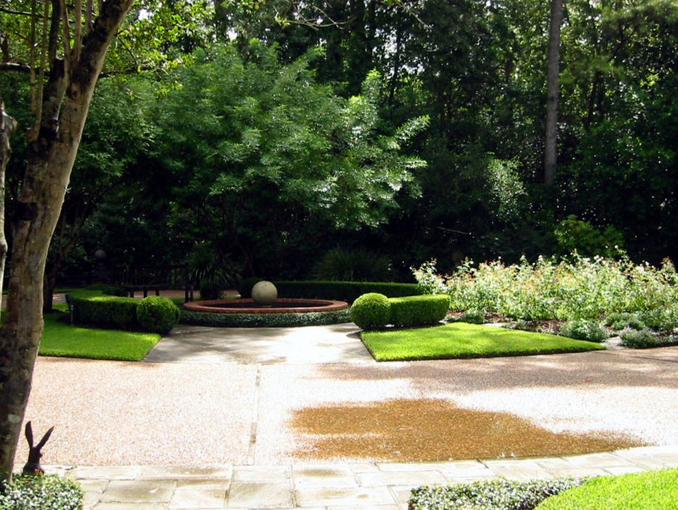 This is an example of a large traditional front yard shaded driveway for spring in Houston with concrete pavers and a water feature.