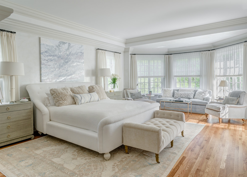 Inspiration for a large traditional master bedroom in New York with white walls, medium hardwood floors and brown floor.