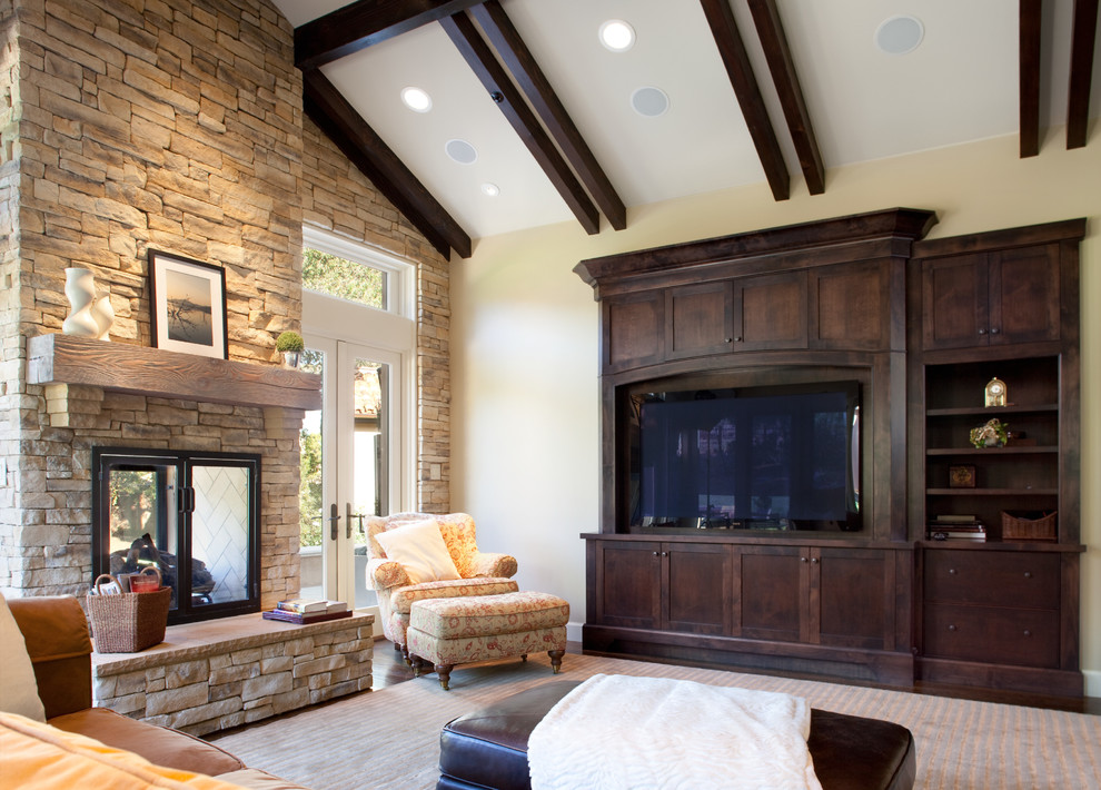 Large mediterranean open concept family room in San Francisco with beige walls, a two-sided fireplace, a stone fireplace surround, a built-in media wall and carpet.