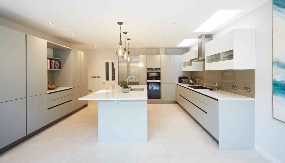 Inspiration for a large contemporary u-shaped kitchen in London with an integrated sink, flat-panel cabinets, grey cabinets, grey splashback, glass sheet splashback, panelled appliances, porcelain floors, with island, white floor and white benchtop.