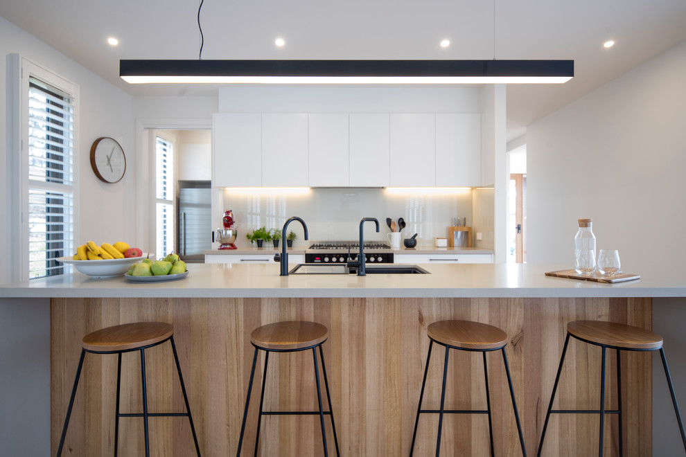 Photo of a large contemporary kitchen in Geelong with an undermount sink, flat-panel cabinets, white cabinets, quartz benchtops, glass sheet splashback, with island, grey splashback and grey benchtop.