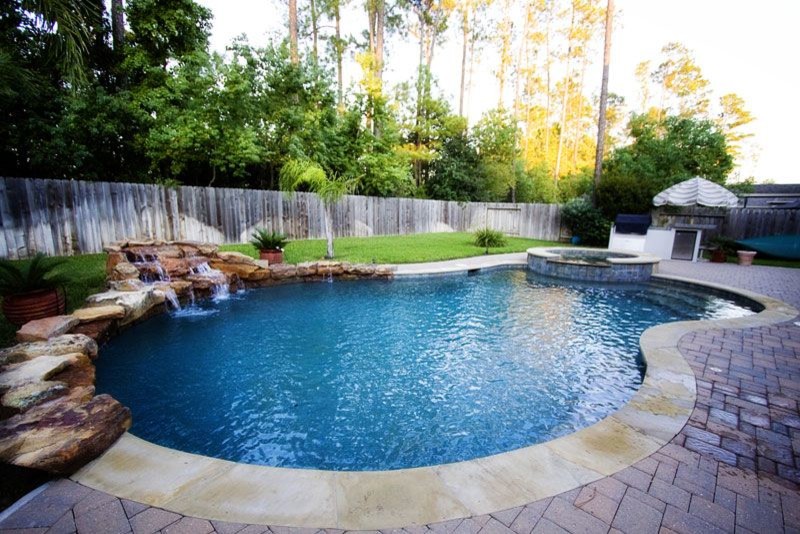 Large backyard brick and custom-shaped natural pool photo in Austin