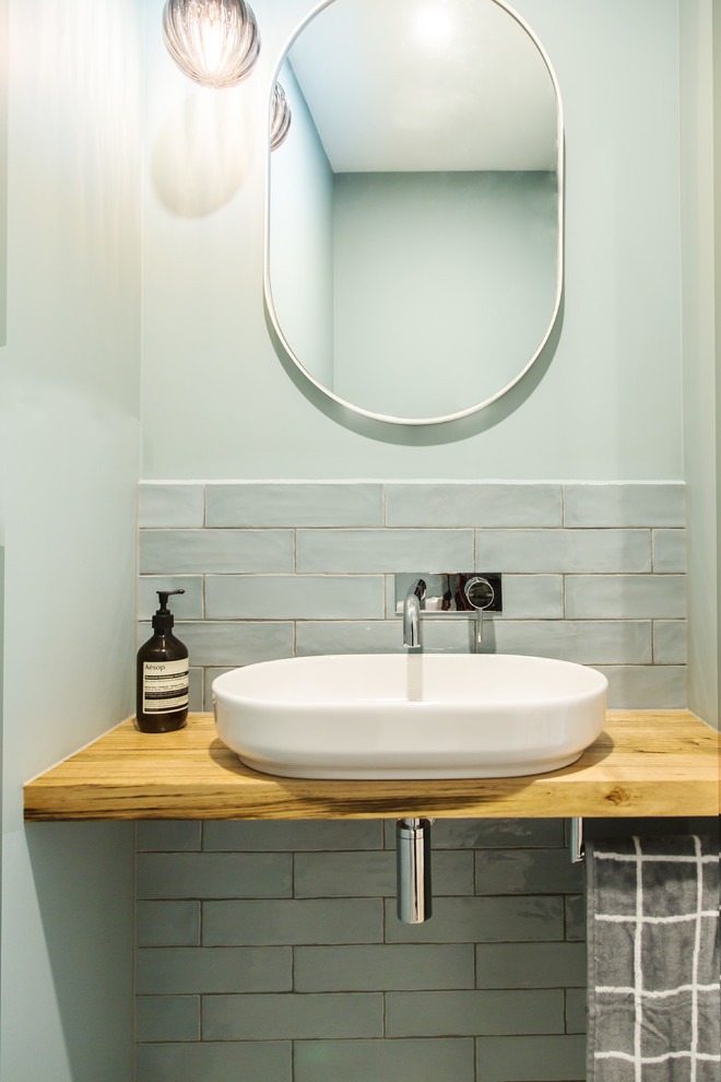 Small modern bathroom in Melbourne with a one-piece toilet, brown tile, ceramic tile, green walls, porcelain floors, a vessel sink, wood benchtops, grey floor and brown benchtops.