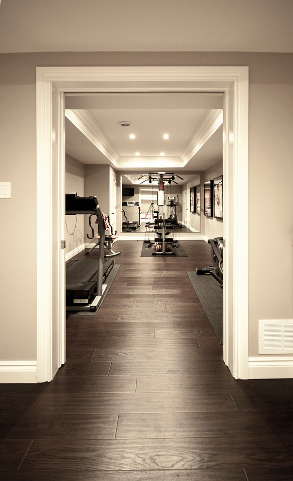 This is an example of a large transitional home weight room in Ottawa with beige walls, dark hardwood floors and brown floor.