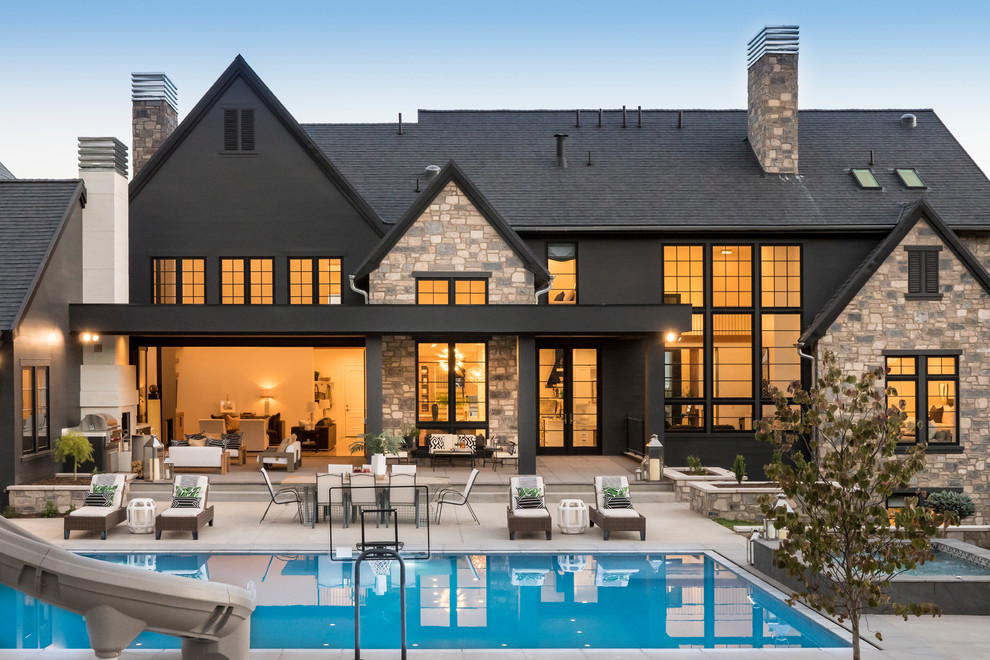 Expansive two-storey black house exterior in New York with stone veneer, a gable roof and a shingle roof.