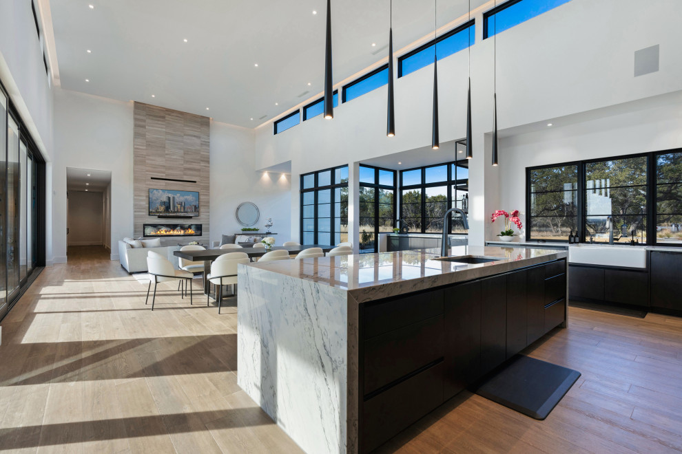 Example of a huge one-story multicolored, medium tone wood floor and brown floor eat-in kitchen design with a farmhouse sink, flat-panel cabinets, dark wood cabinets, stainless steel appliances, an island and white countertops