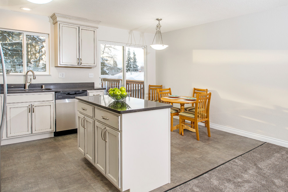 Small transitional l-shaped vinyl floor and gray floor eat-in kitchen photo with a double-bowl sink, recessed-panel cabinets, white cabinets, quartz countertops, gray backsplash, stainless steel appliances and an island