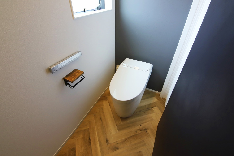 Cette photo montre un WC et toilettes industriel avec un bidet, un mur gris, un sol marron, un plafond en papier peint, du papier peint et un sol en vinyl.