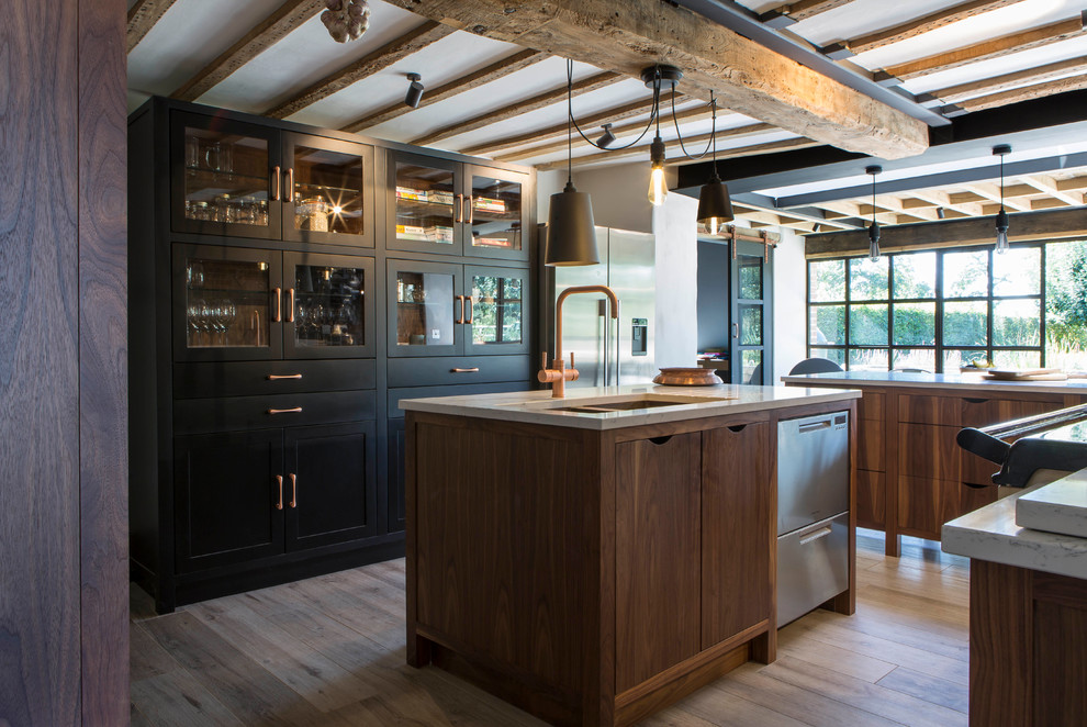 This is an example of a country eat-in kitchen in Oxfordshire with an undermount sink, flat-panel cabinets, medium wood cabinets, stainless steel appliances, light hardwood floors, with island, beige floor and beige benchtop.