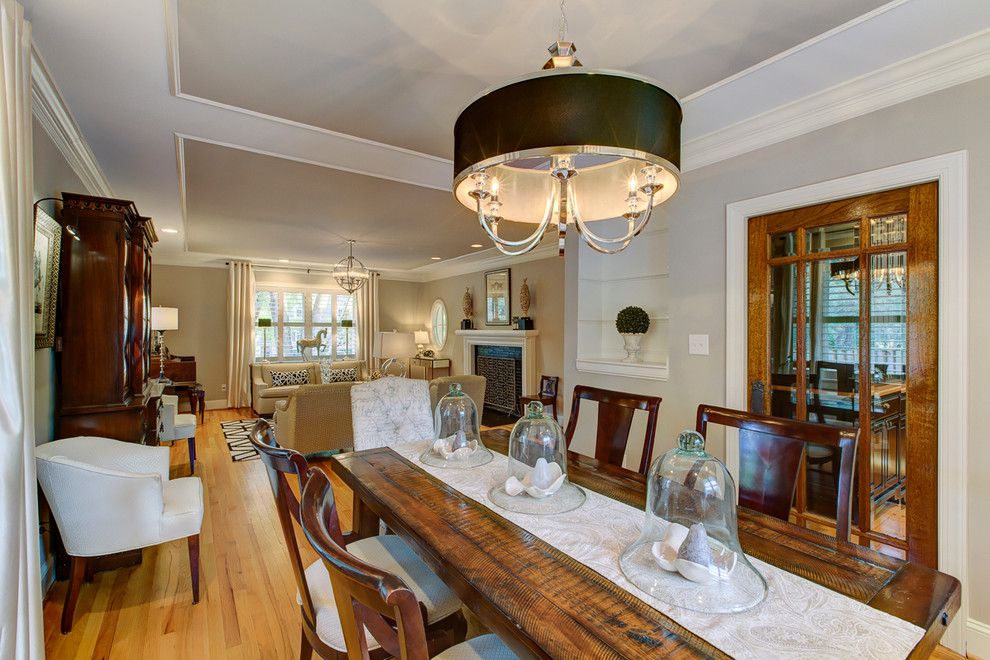 This is an example of a mid-sized transitional open plan dining in Raleigh with beige walls, light hardwood floors, a brick fireplace surround, no fireplace and brown floor.