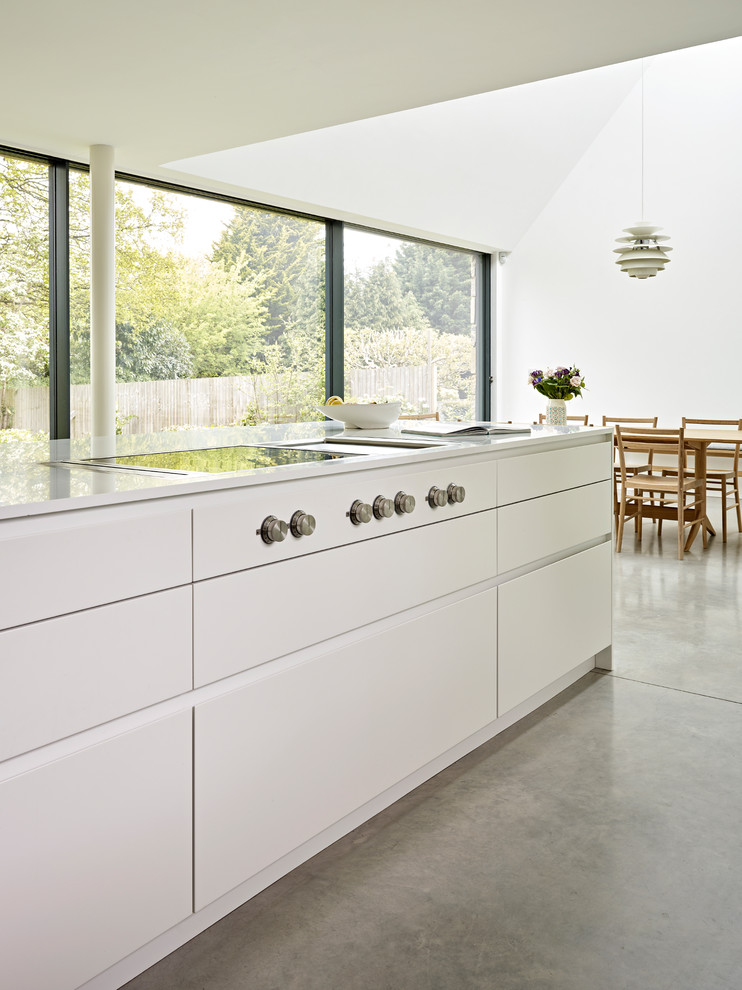 Inspiration for a medium sized scandi single-wall kitchen/diner in Kent with a submerged sink, flat-panel cabinets, white cabinets, composite countertops, white splashback, stainless steel appliances, concrete flooring, an island, grey floors and white worktops.