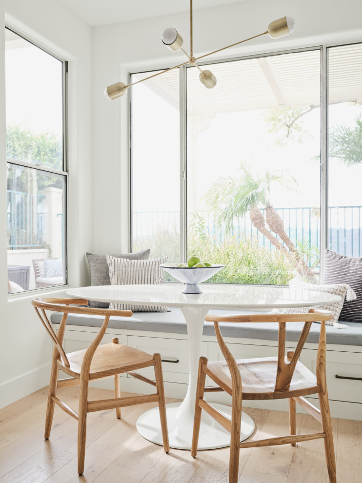 Immagine di un angolo colazione stile marino con pareti bianche e parquet chiaro