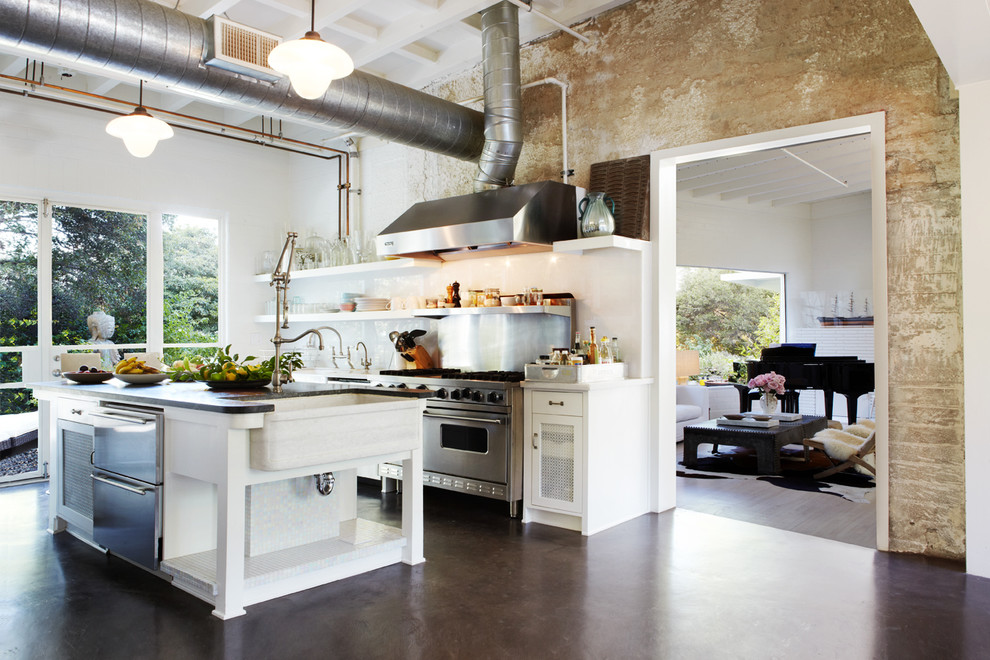 Design ideas for a large industrial separate kitchen in Orange County with a farmhouse sink, white cabinets, solid surface benchtops, metallic splashback, stainless steel appliances, concrete floors, with island, open cabinets and brown floor.