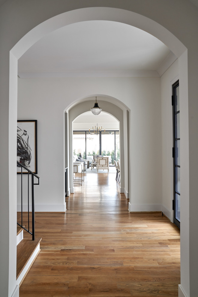 Photo of a mid-sized transitional hallway in Dallas with white walls, medium hardwood floors and beige floor.
