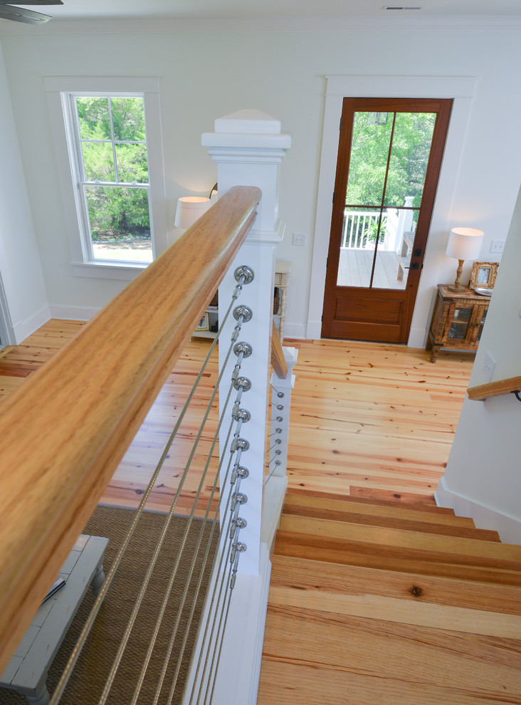 Bild på en mellanstor lantlig l-trappa i trä, med sättsteg i målat trä och kabelräcke