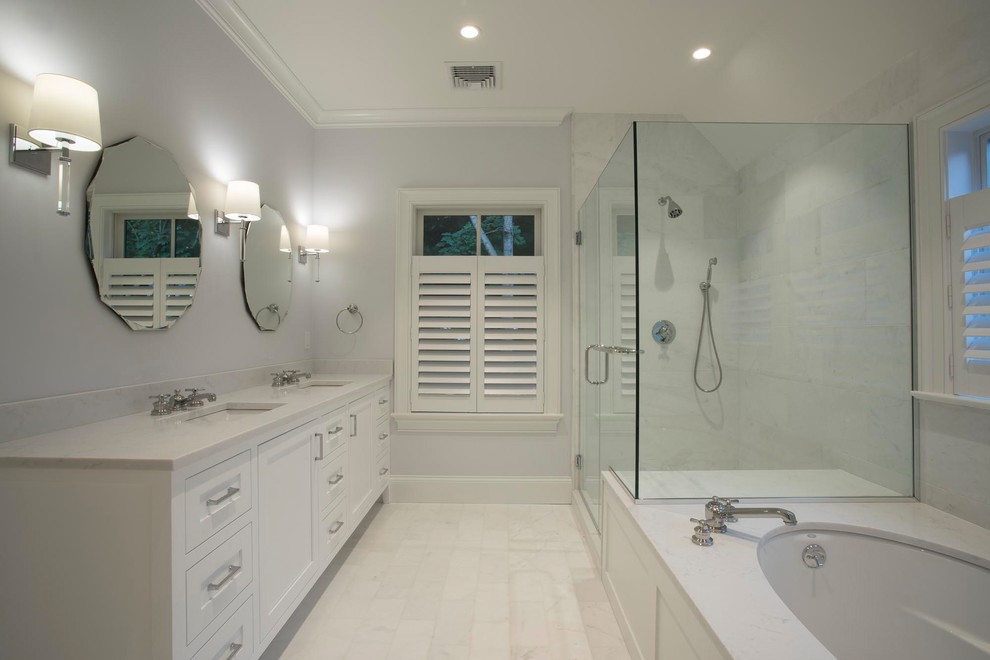 Mid-sized transitional master bathroom in New York with recessed-panel cabinets, white cabinets, white tile, engineered quartz benchtops, white benchtops, an undermount tub, a corner shower, marble, grey walls, porcelain floors, an undermount sink, white floor and a hinged shower door.