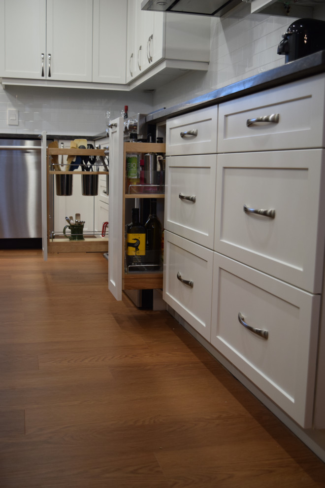 Inspiration for a small transitional u-shaped medium tone wood floor and brown floor open concept kitchen remodel in Ottawa with a farmhouse sink, shaker cabinets, white cabinets, quartz countertops, white backsplash, subway tile backsplash, stainless steel appliances, an island and gray countertops