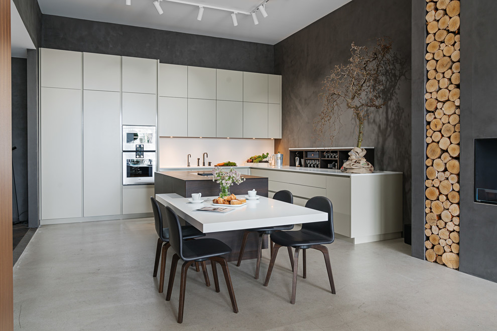 Photo of a large contemporary l-shaped open plan kitchen in Malmo with an undermount sink, flat-panel cabinets, solid surface benchtops, white splashback, stainless steel appliances, concrete floors, with island, grey floor, white benchtop and white cabinets.