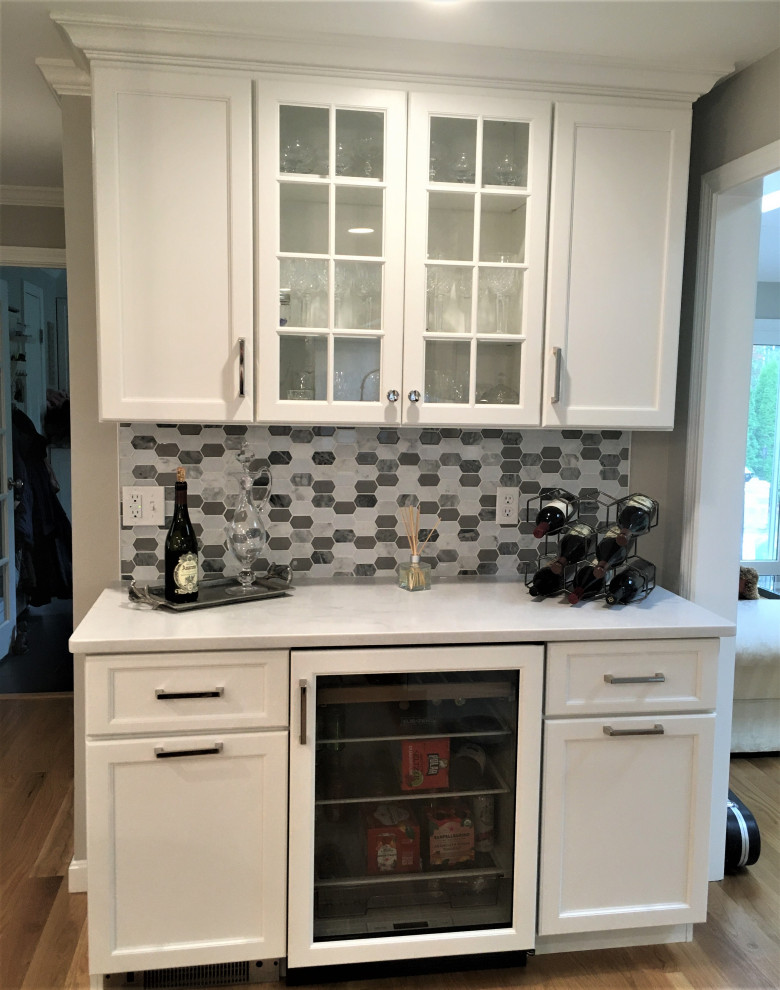 Example of a large transitional galley light wood floor and brown floor eat-in kitchen design in Boston with an undermount sink, shaker cabinets, white cabinets, quartz countertops, white backsplash, subway tile backsplash, stainless steel appliances, two islands and white countertops