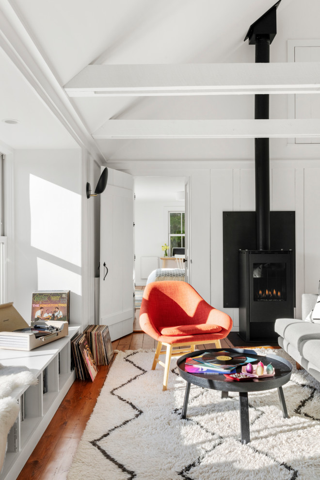 Inspiration for a scandinavian open concept medium tone wood floor and vaulted ceiling living room remodel in Boston with no tv, white walls and a hanging fireplace