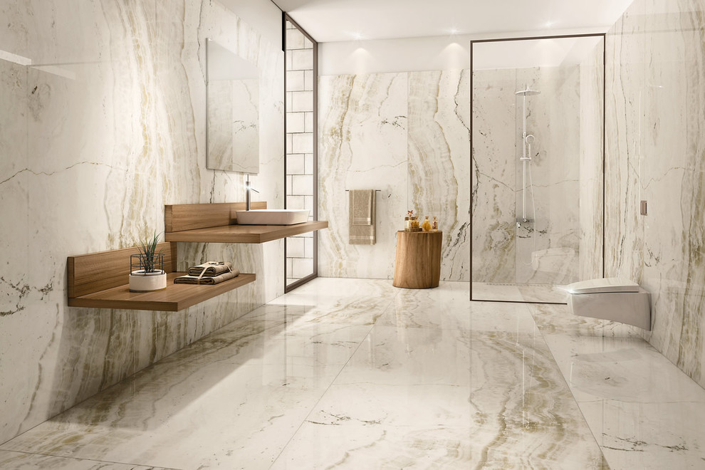 This is an example of a large contemporary master bathroom in San Diego with open cabinets, medium wood cabinets, an open shower, a wall-mount toilet, beige tile, white tile, marble, white walls, marble floors, a vessel sink, wood benchtops, white floor and an open shower.