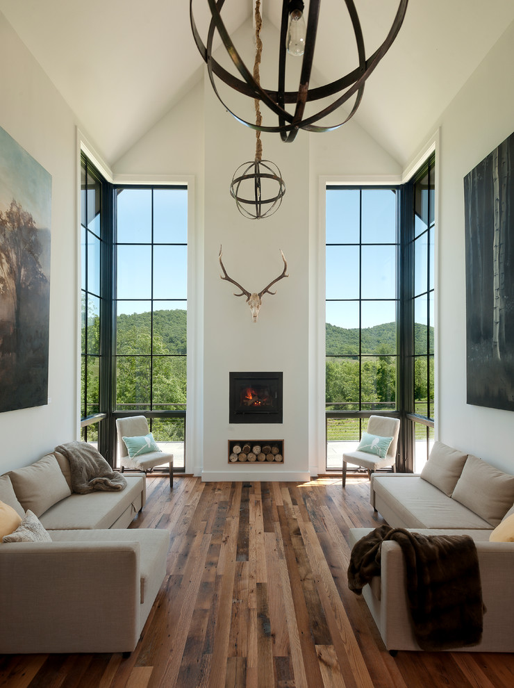This is an example of a contemporary living room in DC Metro with white walls, medium hardwood floors, a standard fireplace, a plaster fireplace surround and brown floor.
