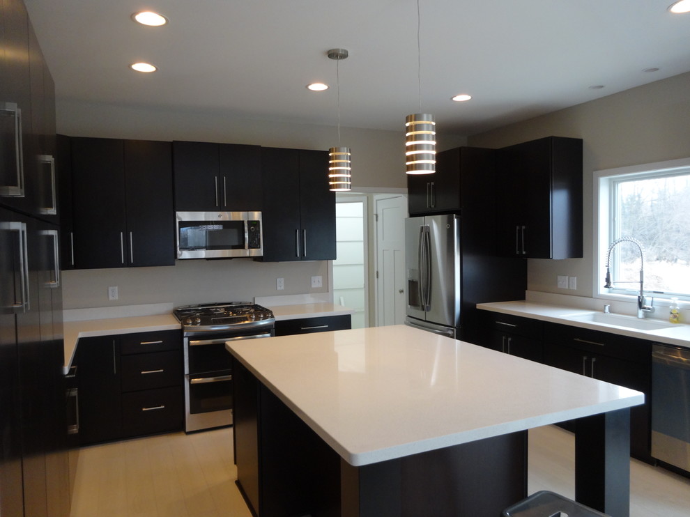 Design ideas for a large modern u-shaped open plan kitchen in Milwaukee with an undermount sink, flat-panel cabinets, dark wood cabinets, quartz benchtops, white splashback, stainless steel appliances, laminate floors and with island.