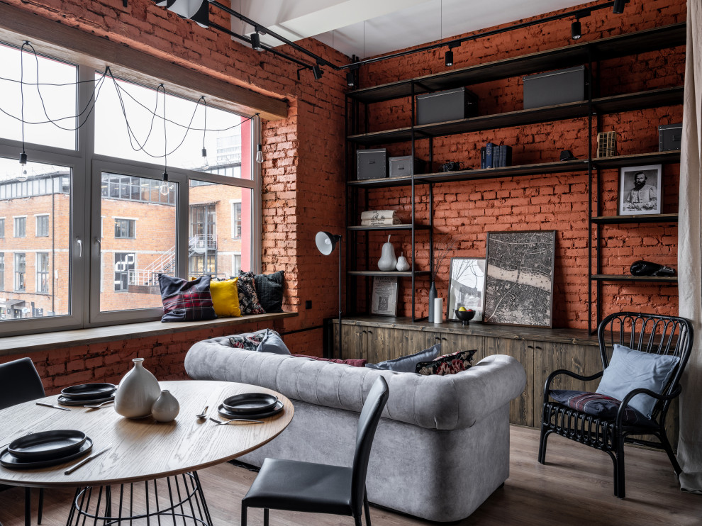Small industrial living room in Moscow with red walls, dark hardwood floors, brown floor, exposed beam and brick walls.