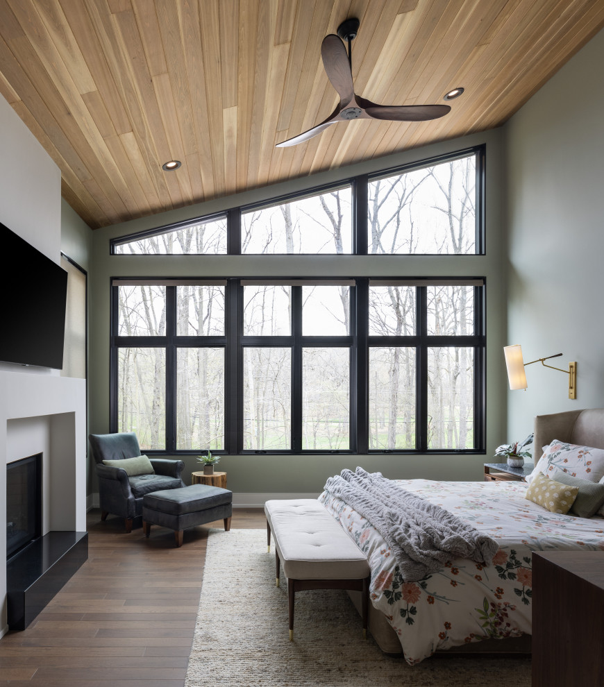 Inspiration for a large transitional master bedroom in Detroit with green walls, dark hardwood floors, a standard fireplace and brown floor.