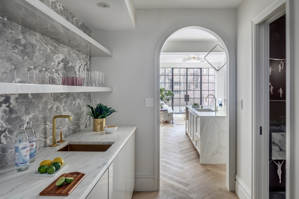 Transitional single-wall kitchen pantry in New York with an undermount sink, flat-panel cabinets, white cabinets, light hardwood floors, white benchtop, marble benchtops, multi-coloured splashback, no island and brown floor.