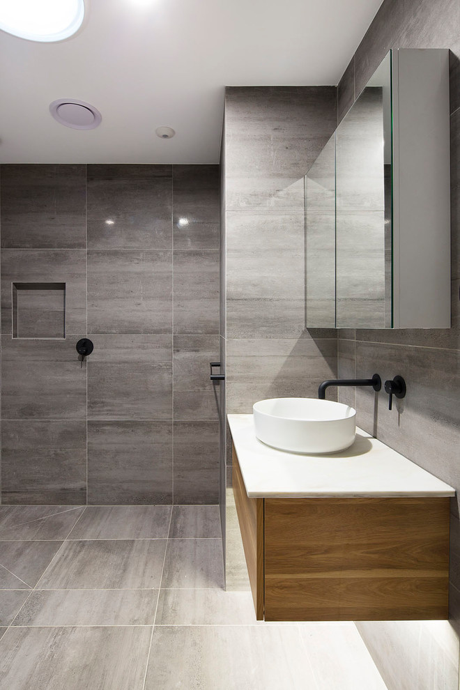 Photo of a mid-sized contemporary bathroom in Brisbane with flat-panel cabinets, light wood cabinets, a freestanding tub, an open shower, gray tile, porcelain tile, grey walls, porcelain floors, a vessel sink, marble benchtops, grey floor and white benchtops.