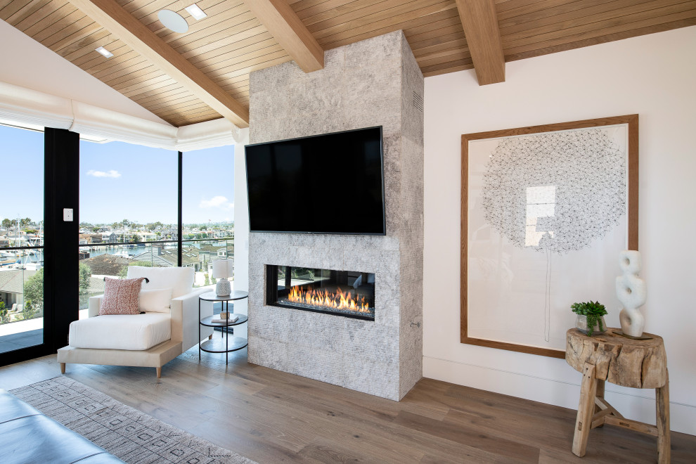 Design ideas for a large transitional master bedroom in Orange County with beige walls, light hardwood floors, a ribbon fireplace, a stone fireplace surround, brown floor, vaulted and wood.