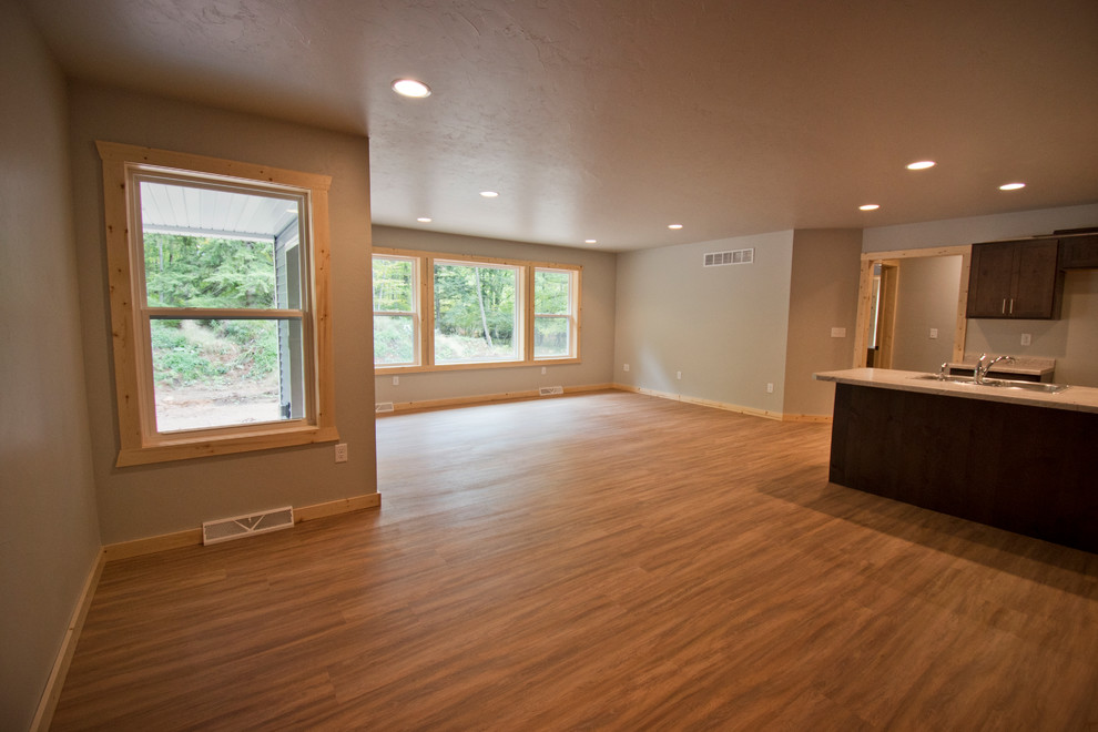 Mid-sized mountain style l-shaped medium tone wood floor and brown floor eat-in kitchen photo with a double-bowl sink, recessed-panel cabinets, dark wood cabinets, an island and gray countertops