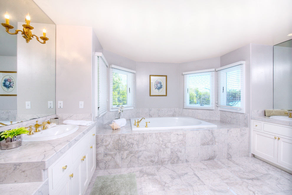 Inspiration for a large traditional master bathroom in San Francisco with a drop-in sink, raised-panel cabinets, white cabinets, wood benchtops, an alcove tub, white tile, stone tile, white walls and marble floors.