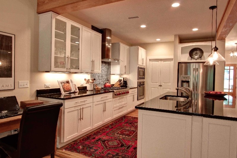 Mid-sized transitional l-shaped light wood floor open concept kitchen photo with an undermount sink, shaker cabinets, white cabinets, granite countertops, multicolored backsplash, mosaic tile backsplash, stainless steel appliances and an island