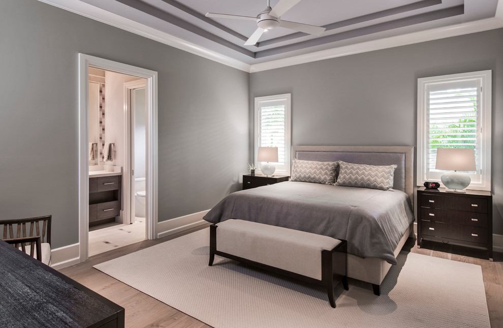 Photo of a mid-sized transitional guest bedroom in Miami with grey walls and light hardwood floors.