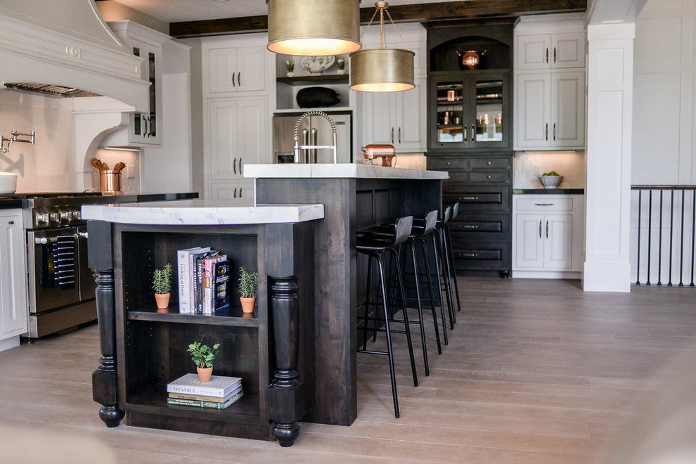Inspiration for a mid-sized transitional l-shaped light wood floor and gray floor eat-in kitchen remodel in Seattle with a farmhouse sink, raised-panel cabinets, white cabinets, marble countertops, white backsplash, subway tile backsplash, stainless steel appliances and an island