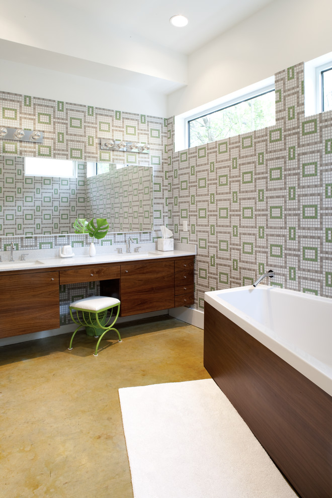 This is an example of a midcentury bathroom in Austin with an undermount sink, flat-panel cabinets, medium wood cabinets, a freestanding tub, multi-coloured tile, mosaic tile, multi-coloured walls and concrete floors.