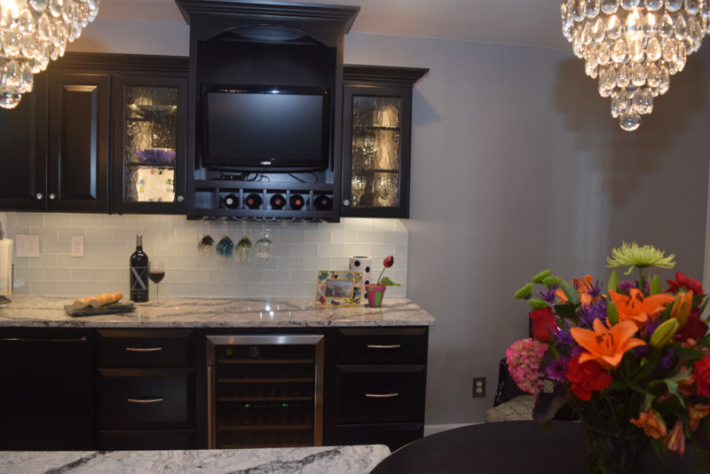 Inspiration for a transitional medium tone wood floor kitchen remodel in Chicago with a farmhouse sink, raised-panel cabinets, black cabinets, quartz countertops, white backsplash, glass tile backsplash, stainless steel appliances and an island