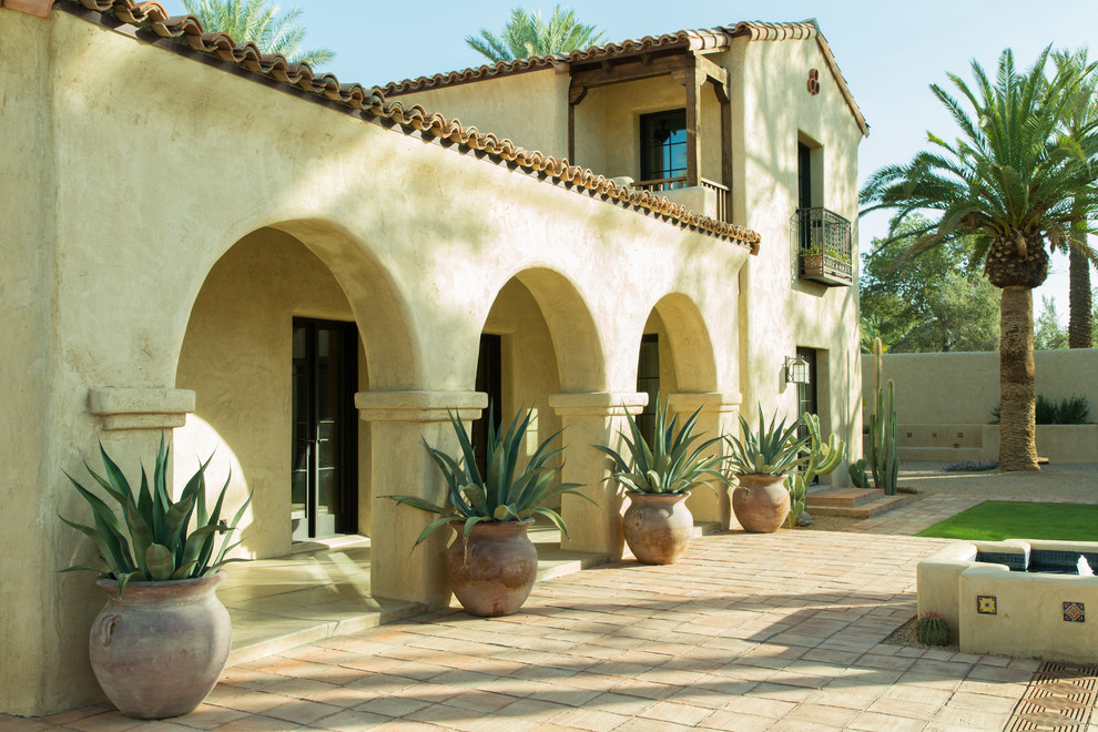 This is an example of an expansive two-storey adobe beige house exterior in Phoenix with a gable roof and a tile roof.