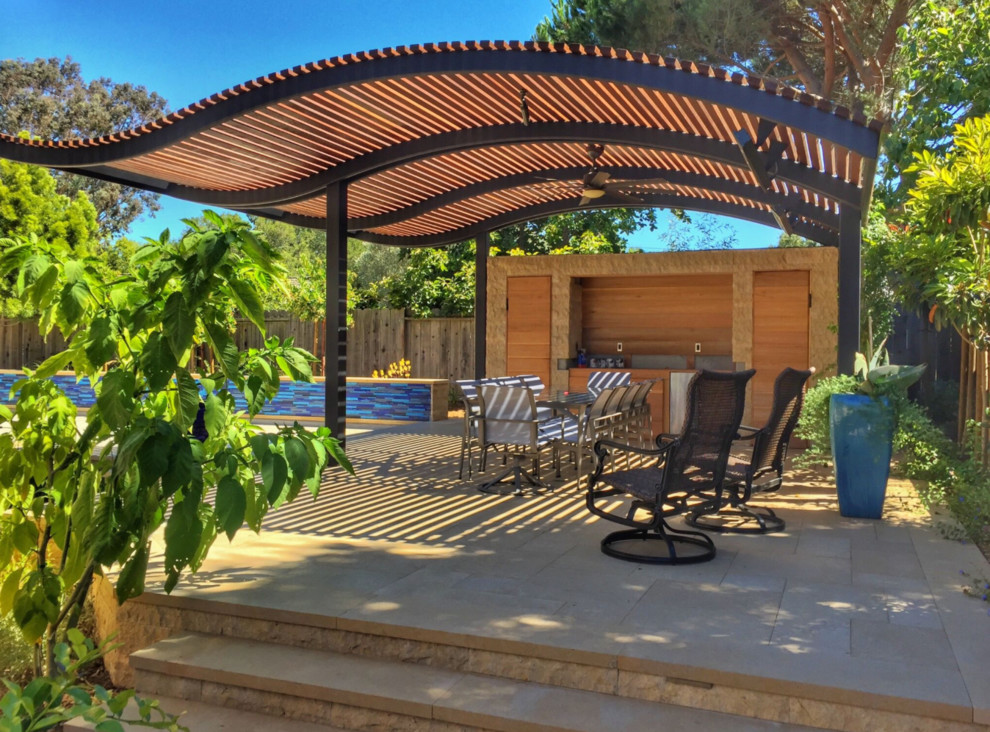 This is an example of a large modern backyard patio in San Francisco with an outdoor kitchen, natural stone pavers and a gazebo/cabana.