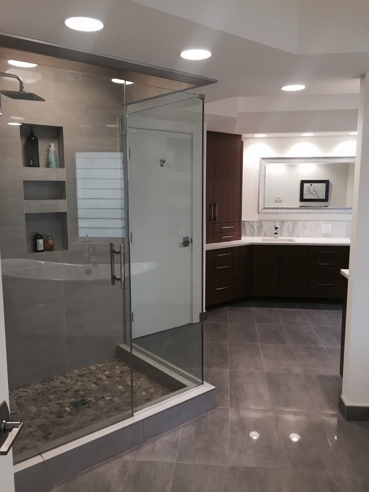Design ideas for an expansive transitional master bathroom in Edmonton with flat-panel cabinets, dark wood cabinets, a freestanding tub, a corner shower, a one-piece toilet, white tile, marble, white walls, porcelain floors, an undermount sink, engineered quartz benchtops, grey floor and a hinged shower door.