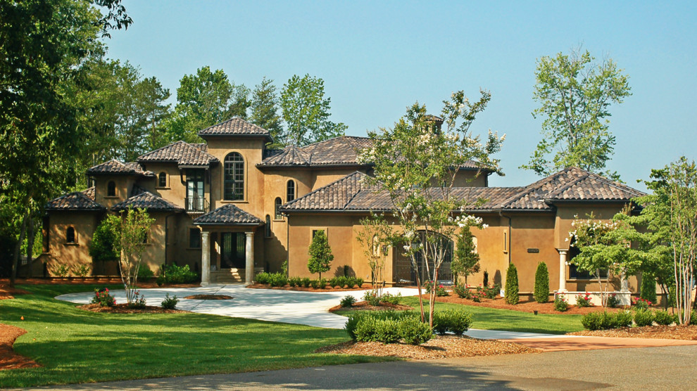 Inspiration for an expansive mediterranean two-storey stucco brown house exterior in Charlotte with a shed roof and a tile roof.