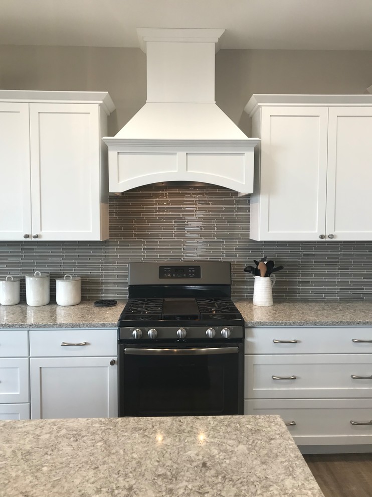 Inspiration for a large transitional l-shaped open concept kitchen remodel in Cedar Rapids with an undermount sink, flat-panel cabinets, white cabinets, quartz countertops, gray backsplash, glass tile backsplash, stainless steel appliances, an island and gray countertops