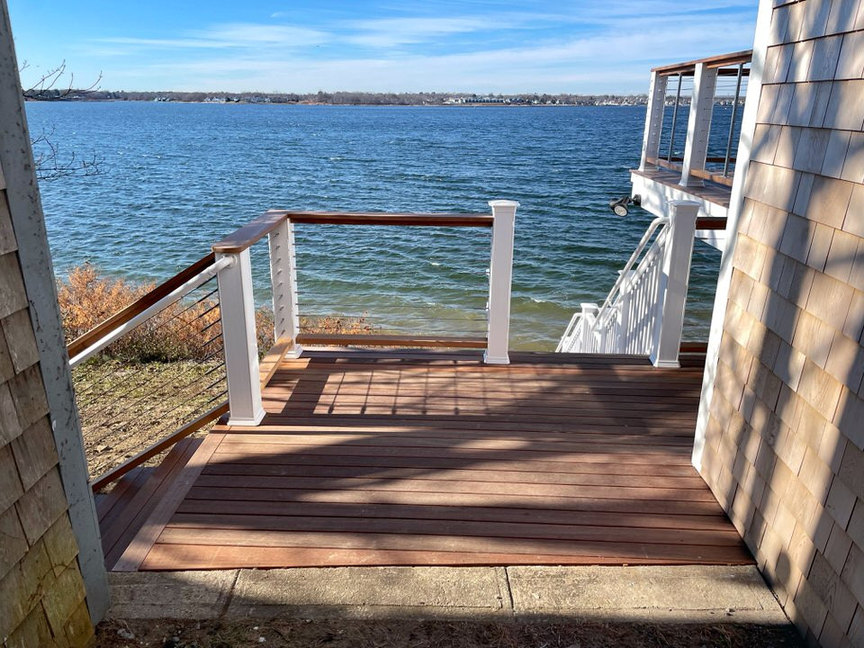 Photo of a small beach style backyard and ground level deck in Providence with no cover and cable railing.