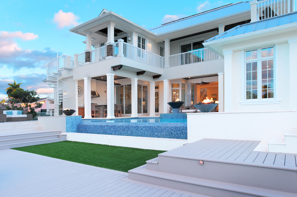 This is an example of an expansive beach style two-storey white exterior in Miami with a hip roof.